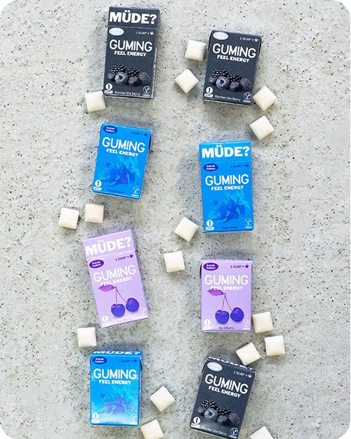 GUMING Energy Koffein Kaugummi mit Guarana und Vitaminen Probier-Paket mit allen Geschmacksrichtungen Fresh Mint Menthol, Kirsch Icy Cherry, Beeren Mix Blacker The Berry auf Betonboden 8 Packungen mit einzelnen Kaugummis drum herum