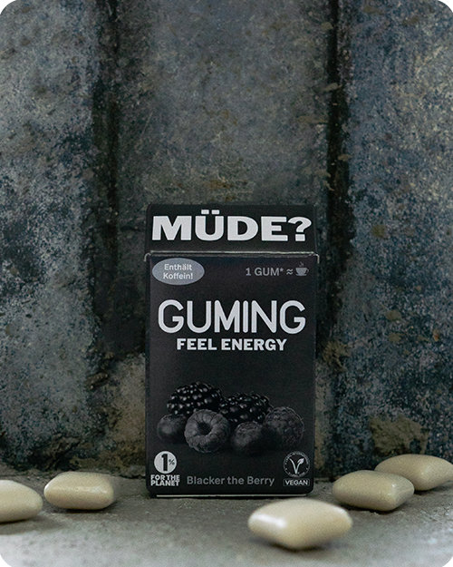 GUMING Energy Koffein Kaugummi mit Guarana und Vitaminen in Geschmacksrichtung Blacker The Berry auf Betonboden mit einzelnen Kaugummis drum herum